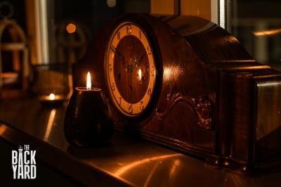 Deux statuettes africaines en gros plan, éclairées par des bougies en arrière-plan dans une ambiance tamisée.