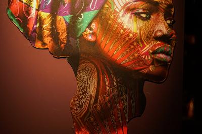 Deux statuettes africaines en gros plan, éclairées par des bougies en arrière-plan dans une ambiance tamisée.