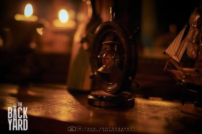 Deux statuettes africaines en gros plan, éclairées par des bougies en arrière-plan dans une ambiance tamisée.