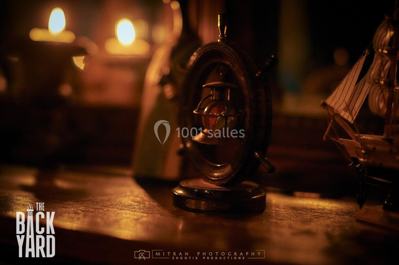 Un gouvernail miniature en bois posé sur une étagère, éclairé par une lumière tamisée et entouré d'objets décoratifs.