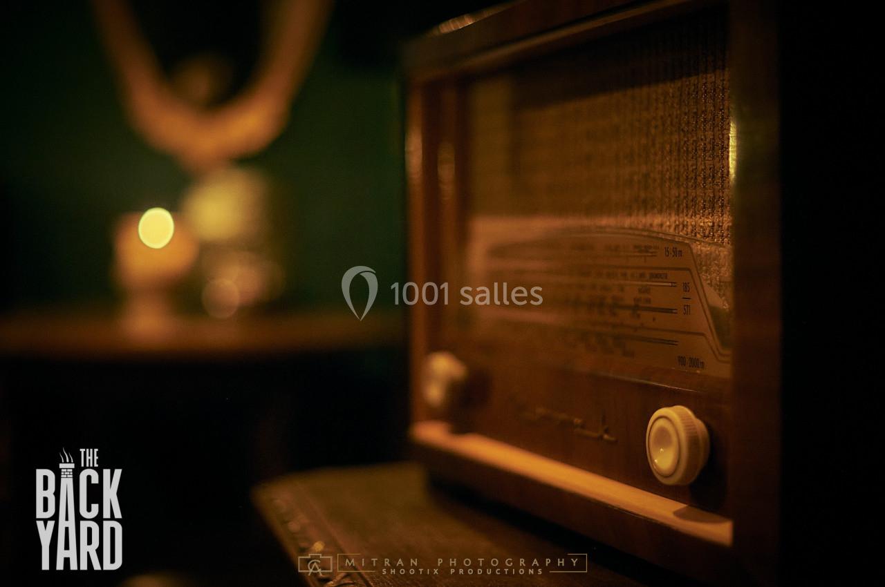 Radio vintage en bois posée sur une table dans une ambiance tamisée avec une lumière douce en arrière-plan.