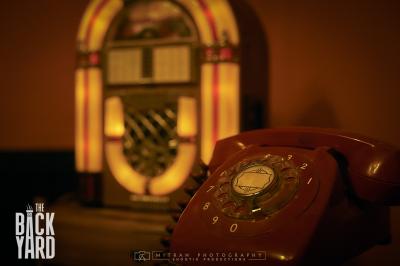 Deux statuettes africaines en gros plan, éclairées par des bougies en arrière-plan dans une ambiance tamisée.