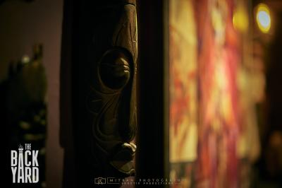 Deux statuettes africaines en gros plan, éclairées par des bougies en arrière-plan dans une ambiance tamisée.