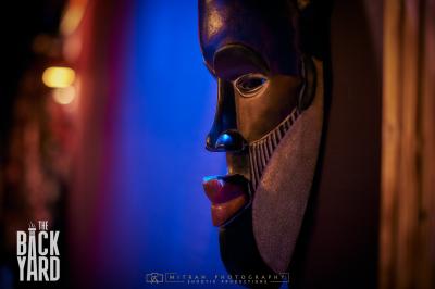 Deux statuettes africaines en gros plan, éclairées par des bougies en arrière-plan dans une ambiance tamisée.