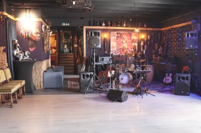 Deux statuettes africaines en gros plan, éclairées par des bougies en arrière-plan dans une ambiance tamisée.