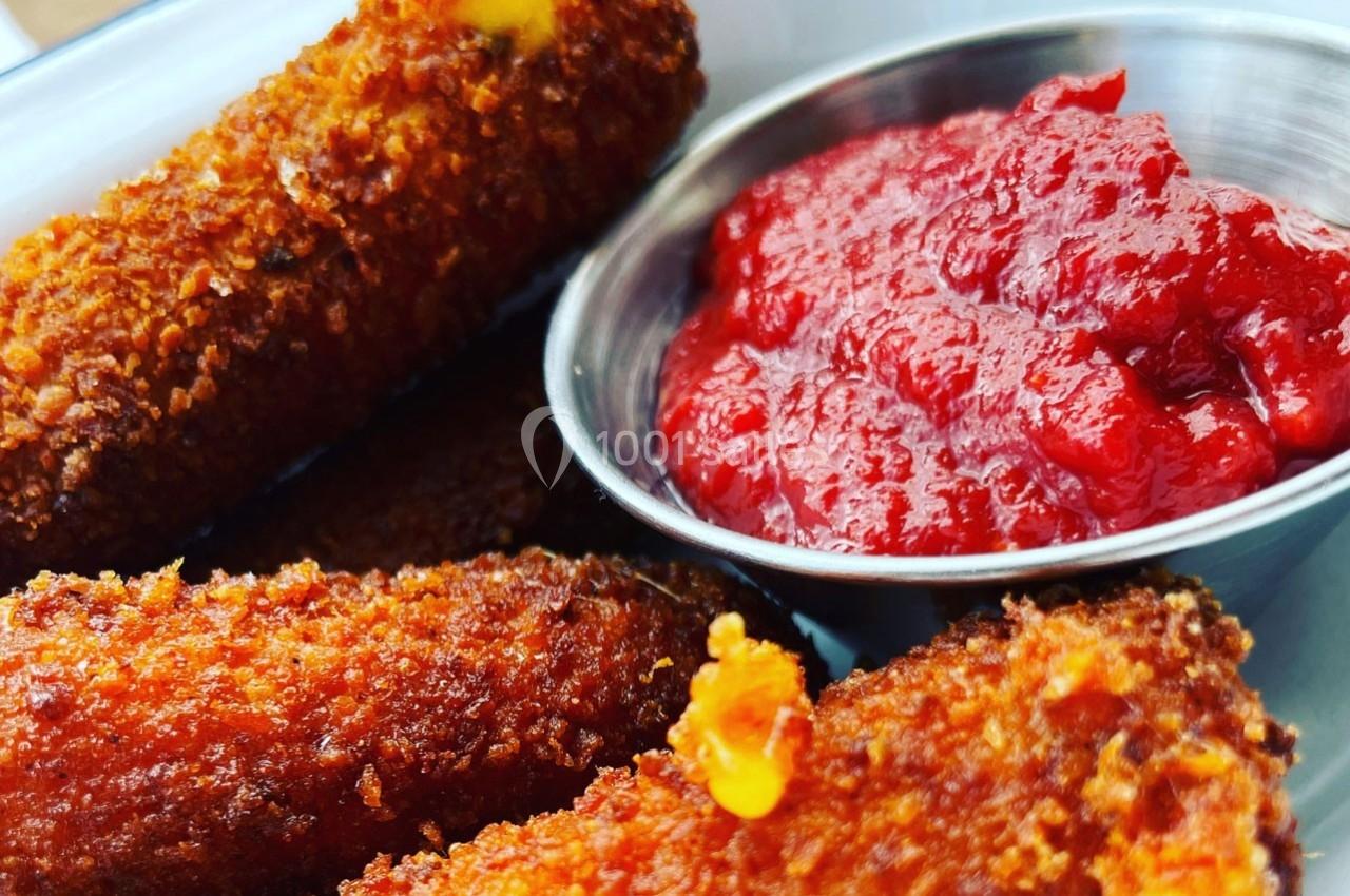 Bâtonnets de fromage panés dorés accompagnés d'une coupelle de sauce tomate.