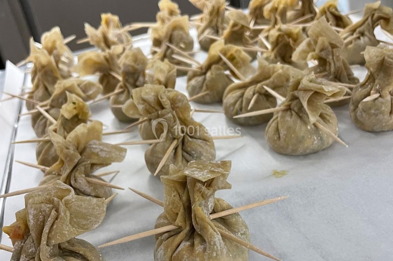 Raviolis en forme de bourses fermées avec des cure-dents, disposés sur une surface blanche.