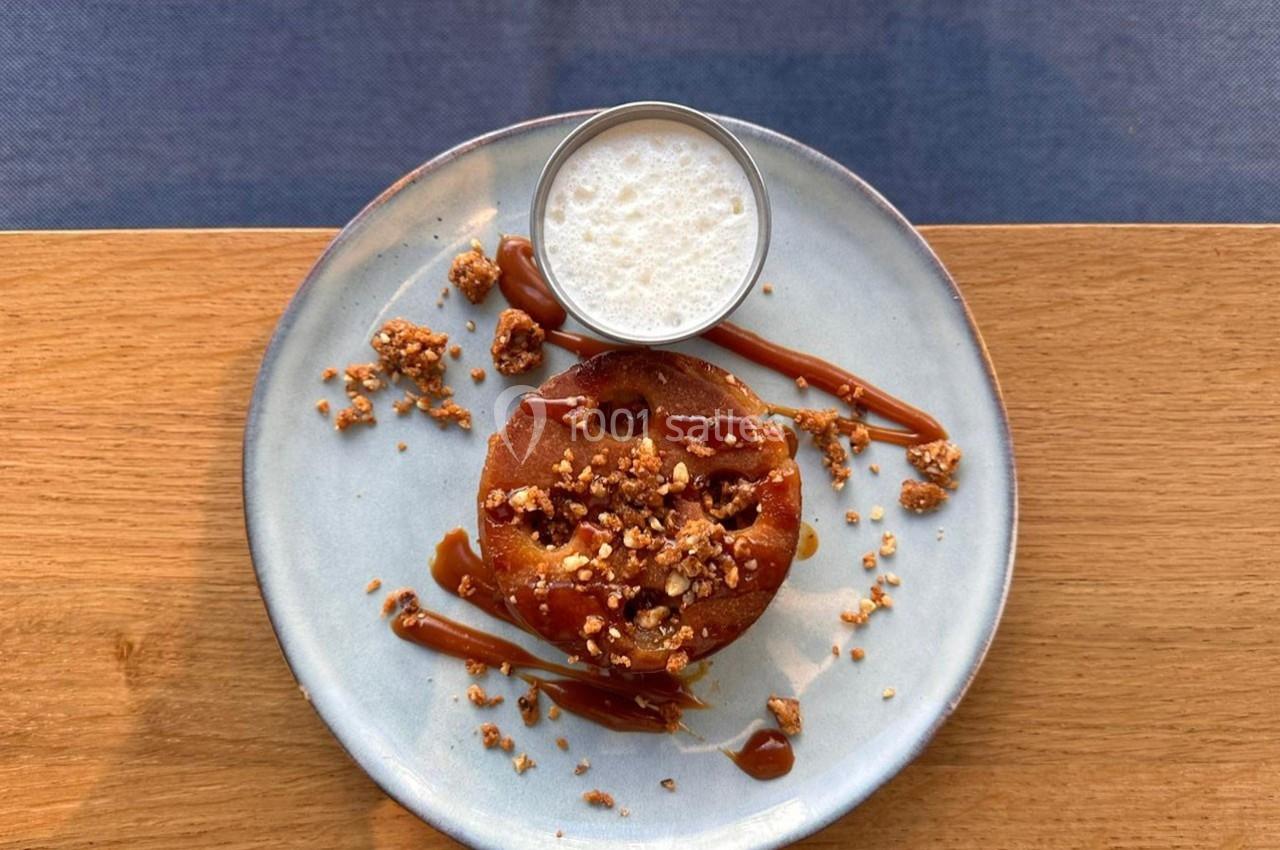 Dessert composé d'un gâteau aux noix caramélisées, sauce caramel et mousse légère, servi sur une assiette claire.