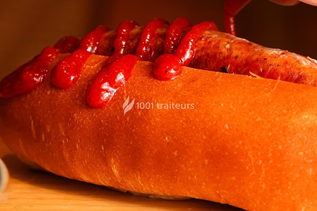 Saucisse grillée dans un pain moelleux, garnie de ketchup appliqué en zigzag.