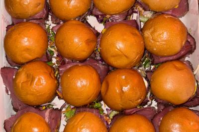 Plateau de mini-burgers au pain brioché, garnis de viande et de légumes colorés.