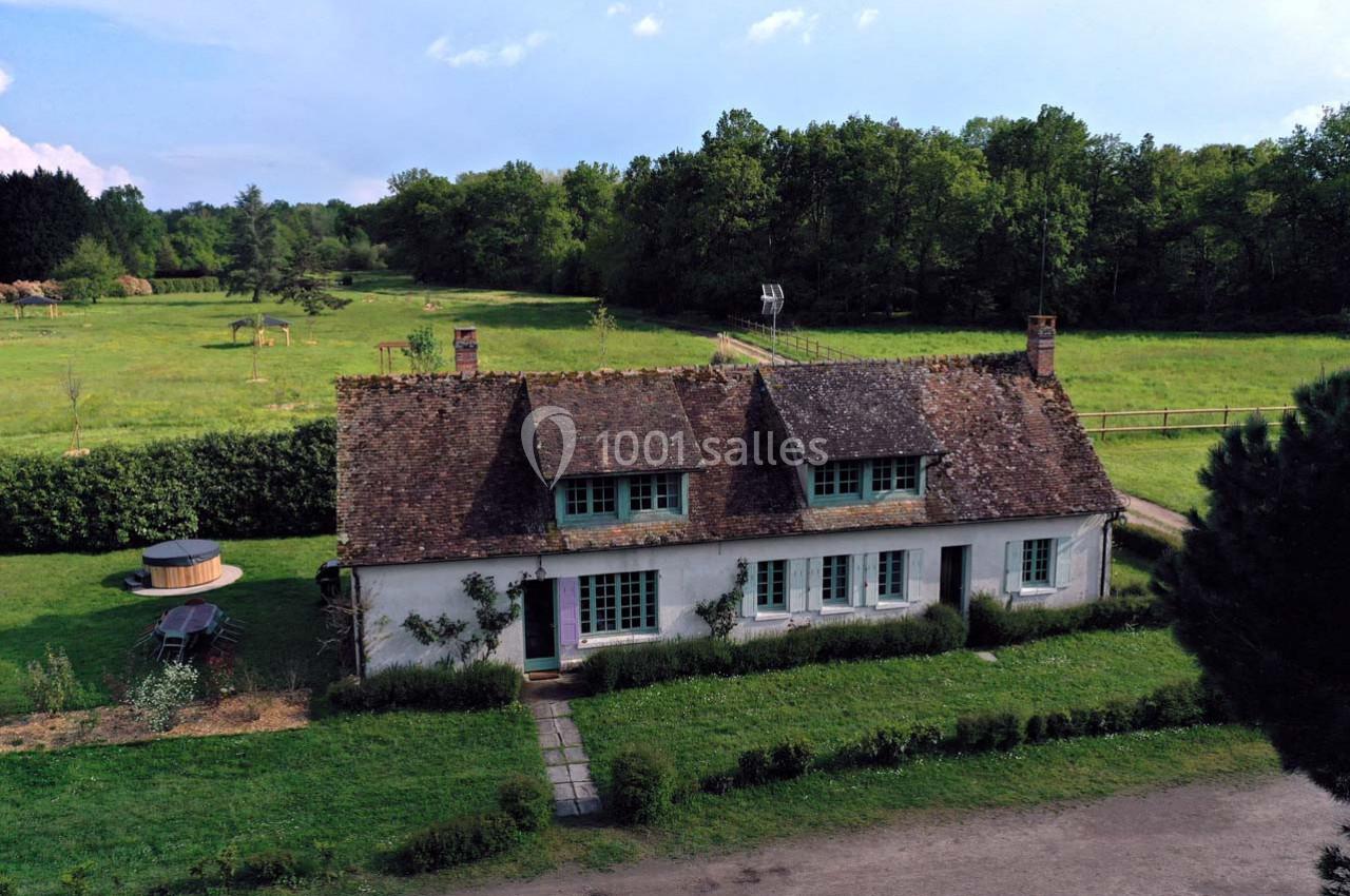 Maison traditionnelle avec toit en tuiles, entourée de verdure, située dans un cadre champêtre avec un jacuzzi extérieur.