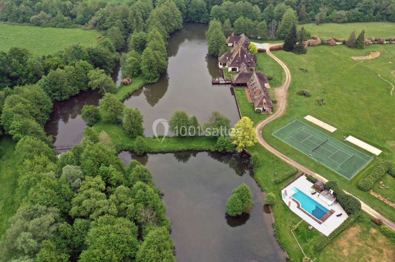 Vue aérienne d'un domaine avec étang, bâtiments anciens, piscine, terrains de tennis et espaces verts environnants.