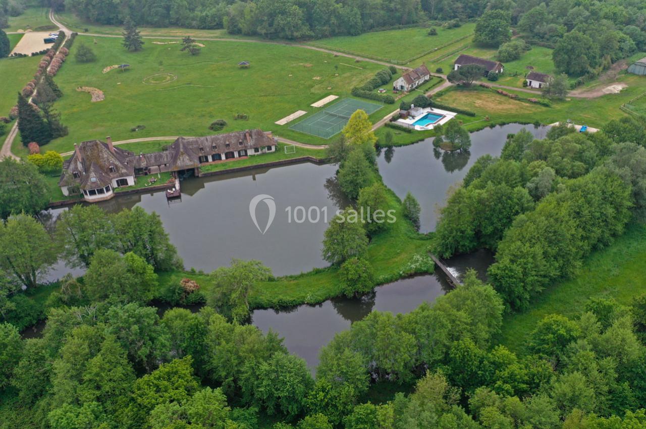 Vue aérienne d'un domaine avec étangs, bâtiments traditionnels, piscine et espaces verts entourés de forêt.