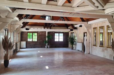 Salle de réception décorée avec des tables rondes dressées, nappes blanches, verres et couverts élégants.