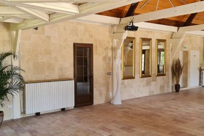 Salle de réception décorée avec des tables rondes dressées, nappes blanches, verres et couverts élégants.