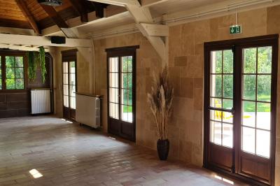 Salle de réception décorée avec des tables rondes dressées, nappes blanches, verres et couverts élégants.