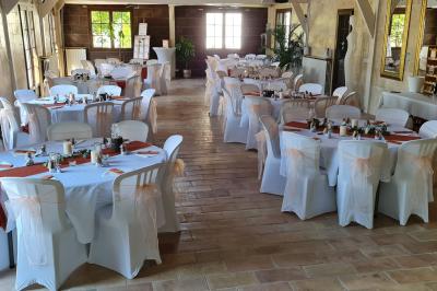Salle de réception décorée avec des tables rondes dressées, nappes blanches, verres et couverts élégants.