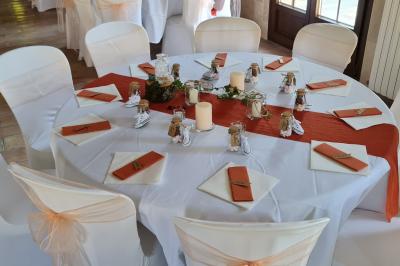 Salle de réception décorée avec des tables rondes dressées, nappes blanches, verres et couverts élégants.