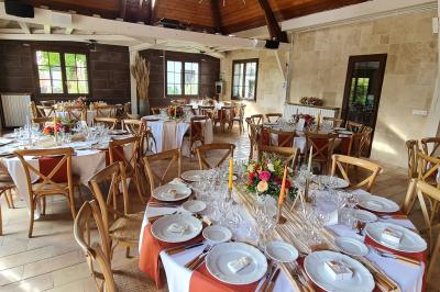 Salle de réception décorée avec des tables rondes dressées, nappes blanches, verres et couverts élégants.