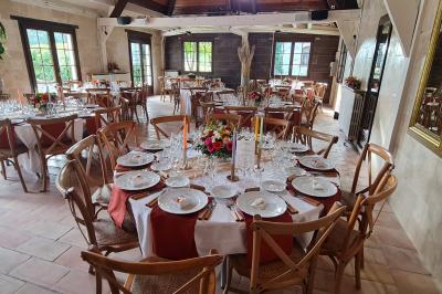Salle de réception décorée avec des tables rondes dressées, nappes blanches, verres et couverts élégants.