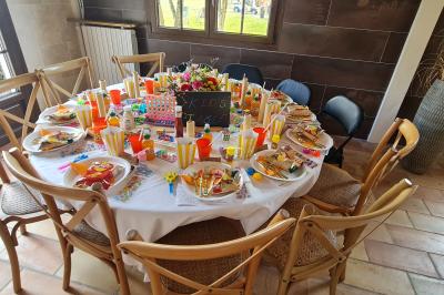 Salle de réception décorée avec des tables rondes dressées, nappes blanches, verres et couverts élégants.
