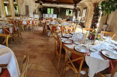 Salle de réception décorée avec des tables rondes dressées, nappes blanches, verres et couverts élégants.