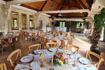 Salle de réception décorée avec des tables rondes dressées, nappes blanches, verres et couverts élégants.