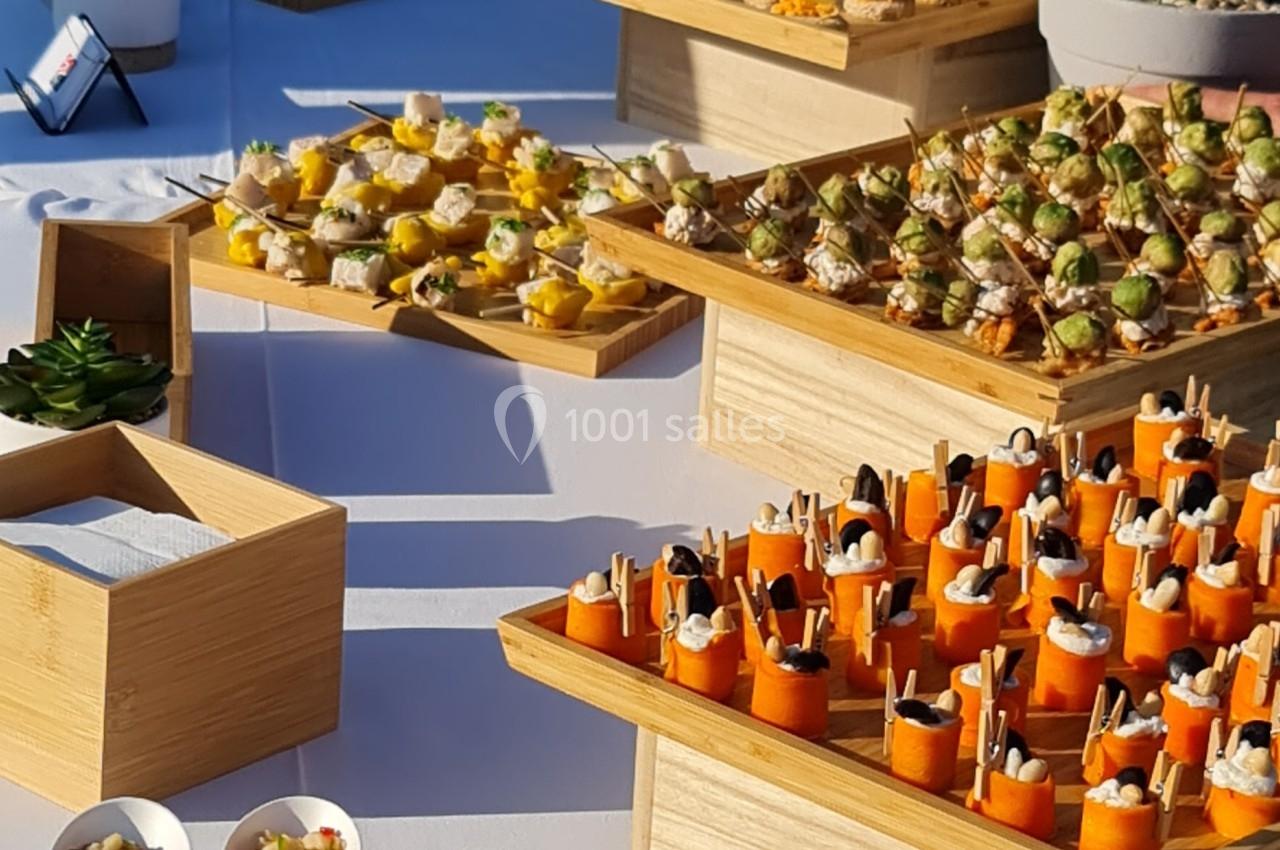 Buffet en extérieur avec une variété de bouchées apéritives présentées sur des plateaux et des bols.