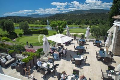 Groupe de personnes dînant en plein air sur une terrasse avec vue sur un paysage verdoyant et des collines au coucher du…