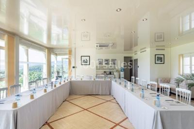 Groupe de personnes dînant en plein air sur une terrasse avec vue sur un paysage verdoyant et des collines au coucher du…