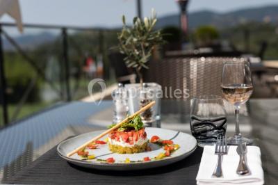 Groupe de personnes dînant en plein air sur une terrasse avec vue sur un paysage verdoyant et des collines au coucher du…