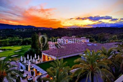 Groupe de personnes dînant en plein air sur une terrasse avec vue sur un paysage verdoyant et des collines au coucher du…