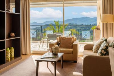 Groupe de personnes dînant en plein air sur une terrasse avec vue sur un paysage verdoyant et des collines au coucher du…