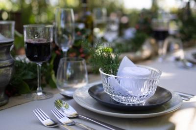 Table élégamment dressée avec chandeliers noirs, verres en cristal et nappes blanches dans une salle au style rustique.