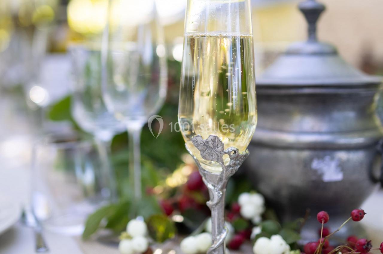 Verre de champagne décoré sur une table dressée avec des éléments naturels et une soupière en arrière-plan.