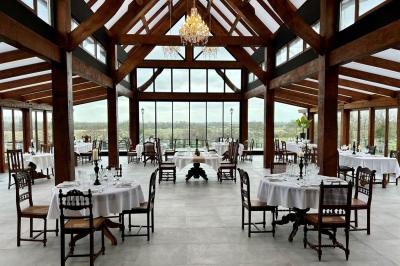 Table élégamment dressée avec chandeliers noirs, verres en cristal et nappes blanches dans une salle au style rustique.