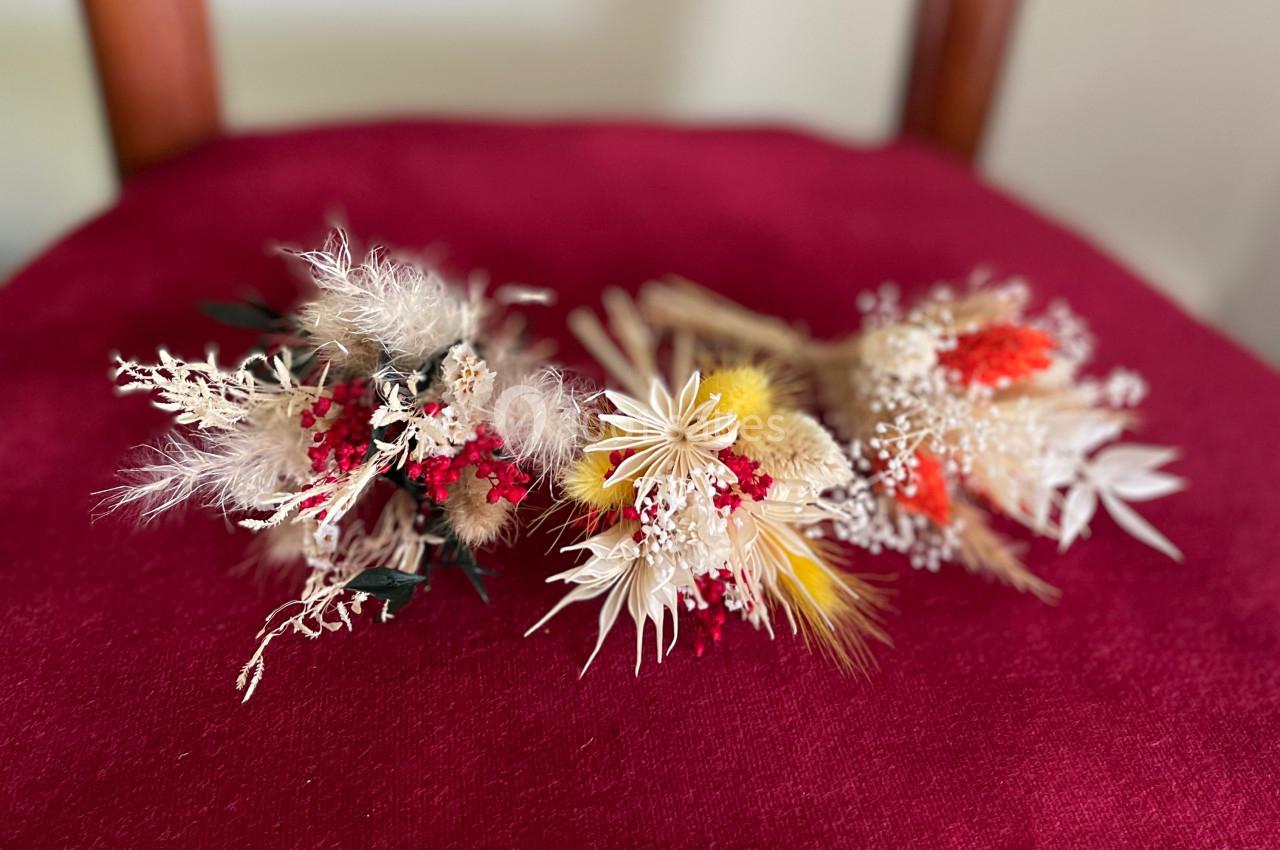 Bouquets de fleurs séchées aux teintes naturelles et rouges, posés sur un tissu rouge.