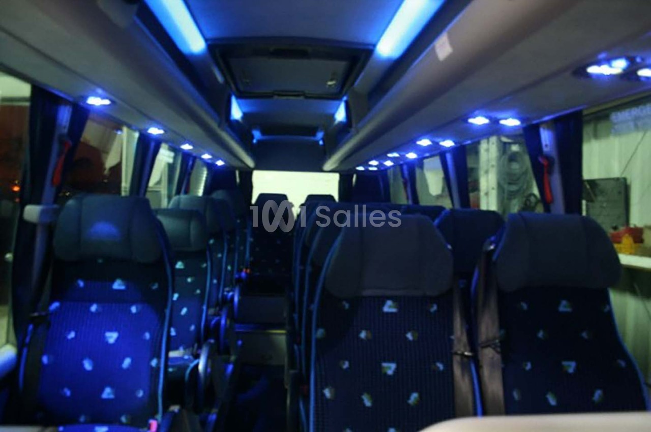 Intérieur d'un minibus avec sièges bleus et éclairage LED bleu au plafond.