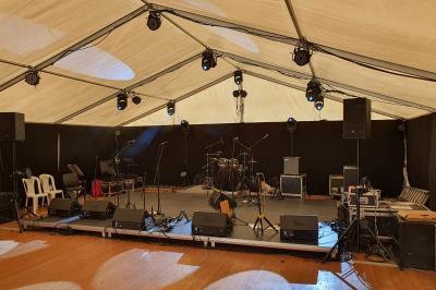 Intérieur d'une tente éclairée en rouge, avec des tables rondes et des chaises blanches disposées pour un événement.