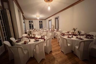Intérieur d'une tente éclairée en rouge, avec des tables rondes et des chaises blanches disposées pour un événement.