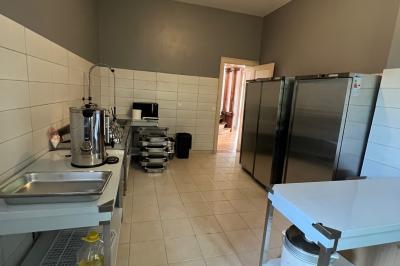 Intérieur d'une tente éclairée en rouge, avec des tables rondes et des chaises blanches disposées pour un événement.