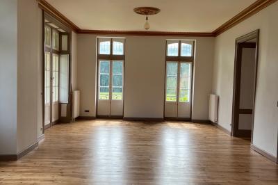 Intérieur d'une tente éclairée en rouge, avec des tables rondes et des chaises blanches disposées pour un événement.