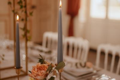 Salle de réception sous une tente avec tables dressées, décorations florales et éclairage suspendu.