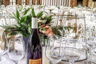 Salle de réception sous une tente avec tables dressées, décorations florales et éclairage suspendu.