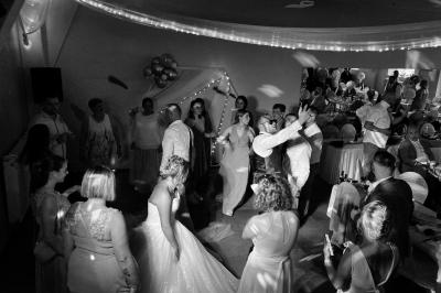 Salle de réception élégante décorée de nappes blanches, chaises habillées et centres de table floraux.