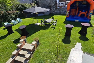 Salle de réception élégante décorée de nappes blanches, chaises habillées et centres de table floraux.