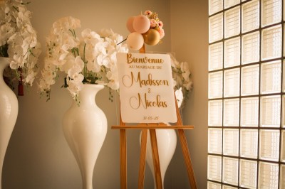 Salle de réception élégante décorée de nappes blanches, chaises habillées et centres de table floraux.