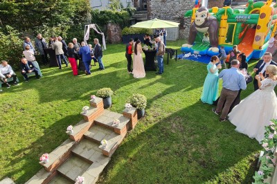 Salle de réception élégante décorée de nappes blanches, chaises habillées et centres de table floraux.