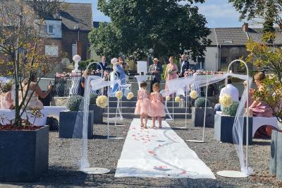 Salle de réception élégante décorée de nappes blanches, chaises habillées et centres de table floraux.