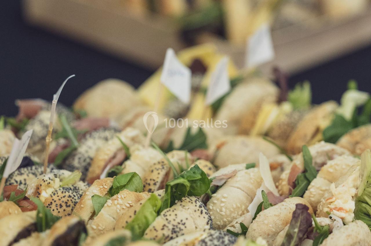 Plateaux de mini-sandwichs variés garnis de légumes, charcuteries et fromages, présentés sur une table noire.